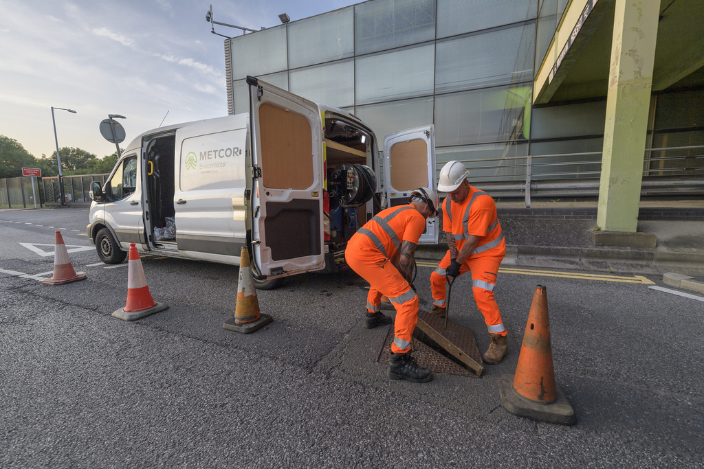 Two engineers lifting manhole cover